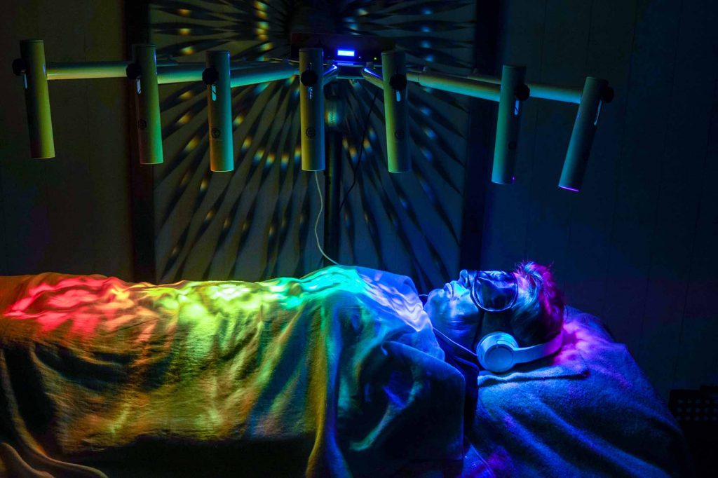 Une personne est installée dans un bain de lumières pour recevoir un super massage sensoriel à Nice.
