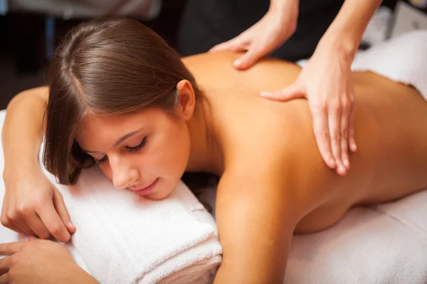 Une jeune femme se relaxe en profitant d'un massage doux et d'une grande sensualité.
