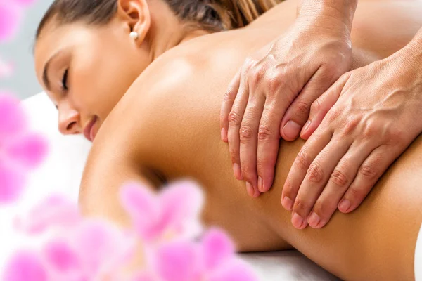 Un masseur masse délicatement le dos d'une femme lors d'un massage body body très sensuel.