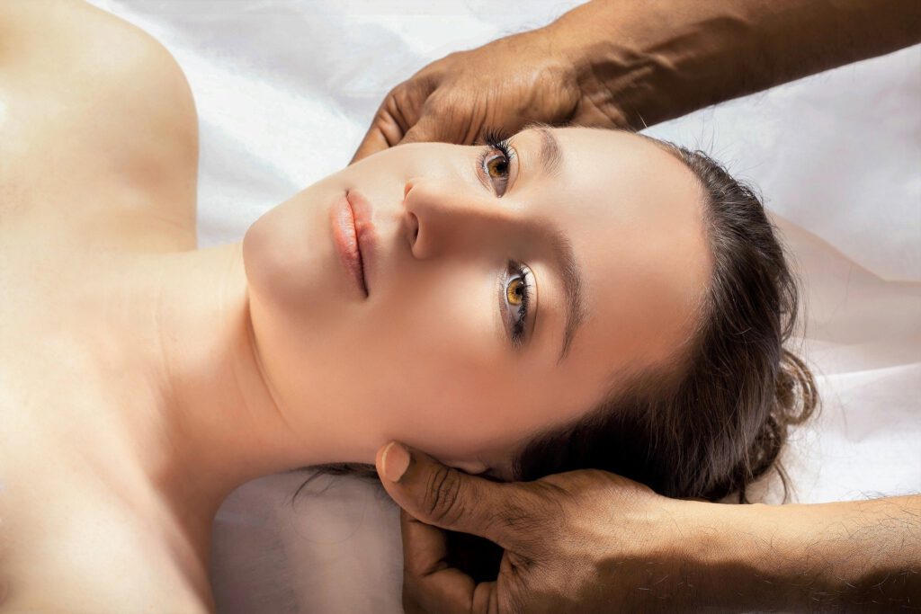 Un masseur masculin masse les 2 côtés du visage d'une femme lors d'un massage relaxant complet.