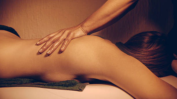 Une jeune femme profite d'un massage tantrique réalisé par une autre femme.