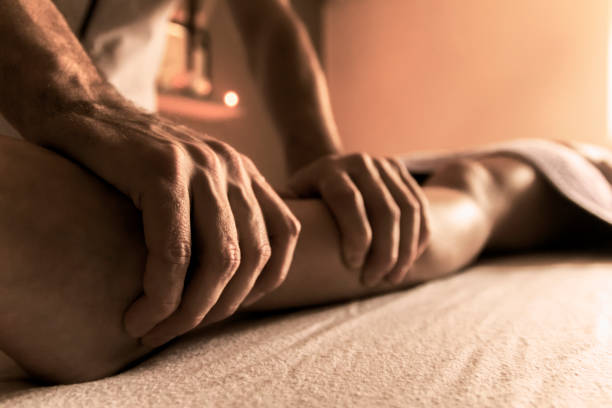 Un masseur masse le mollet gauche d'une femme durant un massage tantrique.