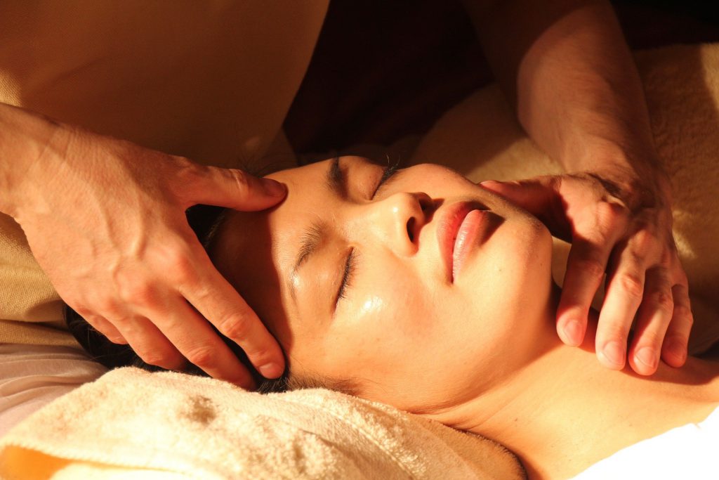 Un masseur homme réalise un massage énergétique sur une femme en travaillant au  niveau de son crâne.